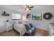 Cozy bedroom with wood-look floors, a ceiling fan, large windows, and a comfortable bed with stylish pillows at 5140 Administration St, Port Charlotte, FL 33948