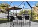 This covered outdoor kitchen with a grill, bar seating, and views of the fenced backyard is perfect for entertaining at 5140 Administration St, Port Charlotte, FL 33948