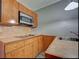 Close up of kitchenette featuring wood cabinets, tile backsplash, stainless steel microwave and smooth cooktop at 602 Bonito Ave, Nokomis, FL 34275