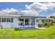 Manicured backyard featuring a striped awning, comfortable seating, and lush green lawn at 608 Fair Winds Dr # 608, Nokomis, FL 34275
