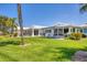 Expansive view of the back of the home and manicured lawn with patio and mature trees at 608 Fair Winds Dr # 608, Nokomis, FL 34275