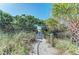 Sandy path to the beach lined with tropical foliage and wooden posts wrapped with nautical rope at 618 Bird Bay S Dr # 110, Venice, FL 34285