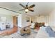 Open-concept living room with wood floors, ceiling fan, adjacent dining, and barn door access to bathroom at 618 Bird Bay S Dr # 110, Venice, FL 34285