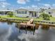 Waterfront home featuring a private dock, manicured lawn, and covered outdoor area perfect for grilling at 700 Blackburn Blvd, North Port, FL 34287