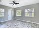Bright bedroom with wood-look tile flooring, a ceiling fan, and windows overlooking the yard at 7140 Teaberry St, Englewood, FL 34224