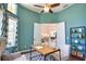 This home office has a ceiling fan, views through large windows, and stylish decor at 8209 Snowy Egret Pl, Bradenton, FL 34202