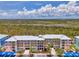 Multi-level condo building featuring colorful facade, covered parking, and tropical landscaping against a scenic natural backdrop at 8409 Placida Rd # 206, Placida, FL 33946