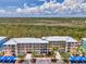 Multi-level condo building featuring colorful facade, covered parking, and tropical landscaping against a scenic natural backdrop at 8409 Placida Rd # 206, Placida, FL 33946