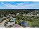 Aerial view of a community with a pool, clubhouse, lake, and lush greenery under a blue sky with clouds at 9118 Coachman Dr, Venice, FL 34293