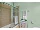 Tiled shower enclosure with glass doors in an airy, bright, mint green bathroom at 9118 Coachman Dr, Venice, FL 34293