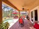 Covered lanai with a dining area and lounge seating overlooks the pool and lush landscaping at 9118 Coachman Dr, Venice, FL 34293