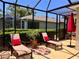 Screened-in porch featuring lounge chairs, red pillows, and a colorful area rug at 9118 Coachman Dr, Venice, FL 34293