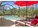 Screened-in pool with lounge chairs and a vibrant red umbrella offers a relaxing outdoor oasis at 9118 Coachman Dr, Venice, FL 34293