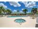 Community pool and hot tub surrounded by lounge chairs, offering a relaxing oasis with an American flag waving at 9118 Coachman Dr, Venice, FL 34293