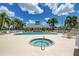Community pool and hot tub surrounded by ample seating, palm trees, and an American flag at 9118 Coachman Dr, Venice, FL 34293