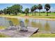 A lakefront backyard with a small dock with two chairs at 915 S Doral Ln, Venice, FL 34293