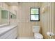 Neutral bathroom featuring striped wallpaper, white vanity, and functional toilet at 915 S Doral Ln, Venice, FL 34293