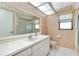 Bright bathroom featuring vanity, framed mirror, and palm-tree themed wallpaper at 915 S Doral Ln, Venice, FL 34293
