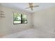 Neutral bedroom with ceiling fan, carpet and large window featuring a palm tree view at 915 S Doral Ln, Venice, FL 34293