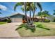 Home features a lush green lawn, mature palm trees, and a well-maintained two-car garage at 915 S Doral Ln, Venice, FL 34293