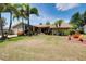 Charming single-story home featuring a lush lawn, mature palm trees, and colorful landscaping under a sunny sky at 915 S Doral Ln, Venice, FL 34293