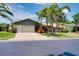 Well-maintained single-story home boasting a lush lawn, mature palm trees, and an attached two-car garage at 915 S Doral Ln, Venice, FL 34293