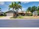 Well-maintained single-story home boasting a lush lawn, mature palm trees, and an attached two-car garage at 915 S Doral Ln, Venice, FL 34293
