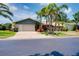 Well-maintained single-story home boasting a lush lawn, mature palm trees, and an attached two-car garage at 915 S Doral Ln, Venice, FL 34293