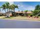 Inviting single-story home with lush landscaping, towering palms, and an attached garage viewed from across the street at 915 S Doral Ln, Venice, FL 34293