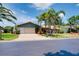 Well-maintained single-story home boasting a lush lawn, mature palm trees, and an attached two-car garage at 915 S Doral Ln, Venice, FL 34293
