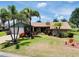 Beautiful single-story home featuring mature palm trees, vibrant landscaping, and a manicured lawn at 915 S Doral Ln, Venice, FL 34293