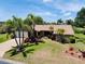 Inviting single-story home showcasing mature palm trees, vibrant landscaping, and a manicured lawn at 915 S Doral Ln, Venice, FL 34293