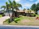 Lovely single-story home featuring mature palm trees, vibrant landscaping, and a well-manicured lawn at 915 S Doral Ln, Venice, FL 34293