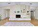 Open living room with stone fireplace, built-in shelving, and neutral decor with wood flooring at 915 S Doral Ln, Venice, FL 34293