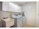 Practical laundry room includes utility sink, washer, dryer, and ample storage cabinets for convenience at 9277 Saint Catherine Ave, Englewood, FL 34224