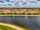 Peaceful aerial view of the complex next to a lake surrounded by lush greenery on a partly cloudy day at 10213 Staggerbush Dr # 202, Venice, FL 34293