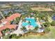 Aerial view of community pool with lush landscaping, lounge chairs, tables, umbrellas, and tennis courts in the background at 10213 Staggerbush Dr # 202, Venice, FL 34293