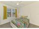 Bright bedroom features a floral-themed quilt, white furniture, and natural light from the windows at 10213 Staggerbush Dr # 202, Venice, FL 34293