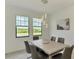 Light-filled dining room featuring modern lighting, neutral decor, and a view of lush landscaping through large windows at 10213 Staggerbush Dr # 202, Venice, FL 34293