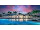 Community pool at dusk, showcasing the beautifully lit clubhouse and surrounding palm trees at 10367 Abaco Falls Dr, Englewood, FL 34223