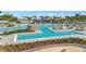 Expansive community pool featuring multiple swimming areas, rock feature, and ample seating, all surrounded by palm trees at 10367 Abaco Falls Dr, Englewood, FL 34223