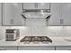 Close up on cooktop with gray cabinets, quartz countertops, and stainless steel appliances at 10367 Abaco Falls Dr, Englewood, FL 34223