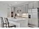 Modern kitchen featuring gray cabinets, stainless steel appliances, a center island, and herringbone tile backsplash at 10367 Abaco Falls Dr, Englewood, FL 34223