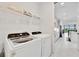 Bright laundry room equipped with modern appliances, complemented by upper shelving at 10367 Abaco Falls Dr, Englewood, FL 34223