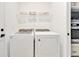 Bright laundry room equipped with modern side by side appliances, complemented by upper shelving at 10367 Abaco Falls Dr, Englewood, FL 34223