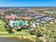 Aerial view of a luxurious community pool surrounded by palm trees and lush landscaping, adjacent to tennis courts at 10789 Tarflower Dr # 202, Venice, FL 34293