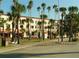 Street view of a light-colored building with tall palm trees, benches, and yellow lines on the road at 1100 Tarpon Center Dr # 503 5C, Venice, FL 34285