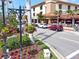 Charming street view, showcasing flowering planters and a building with an outdoor dining area under red umbrellas at 1100 Tarpon Center Dr # 503 5C, Venice, FL 34285