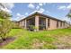 View of the back exterior of home with a screened in patio and lush green grass at 11103 Batello Dr, Venice, FL 34292