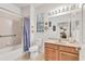 Bathroom with single sink vanity, a large mirror, and a bathtub with a shower curtain at 11103 Batello Dr, Venice, FL 34292